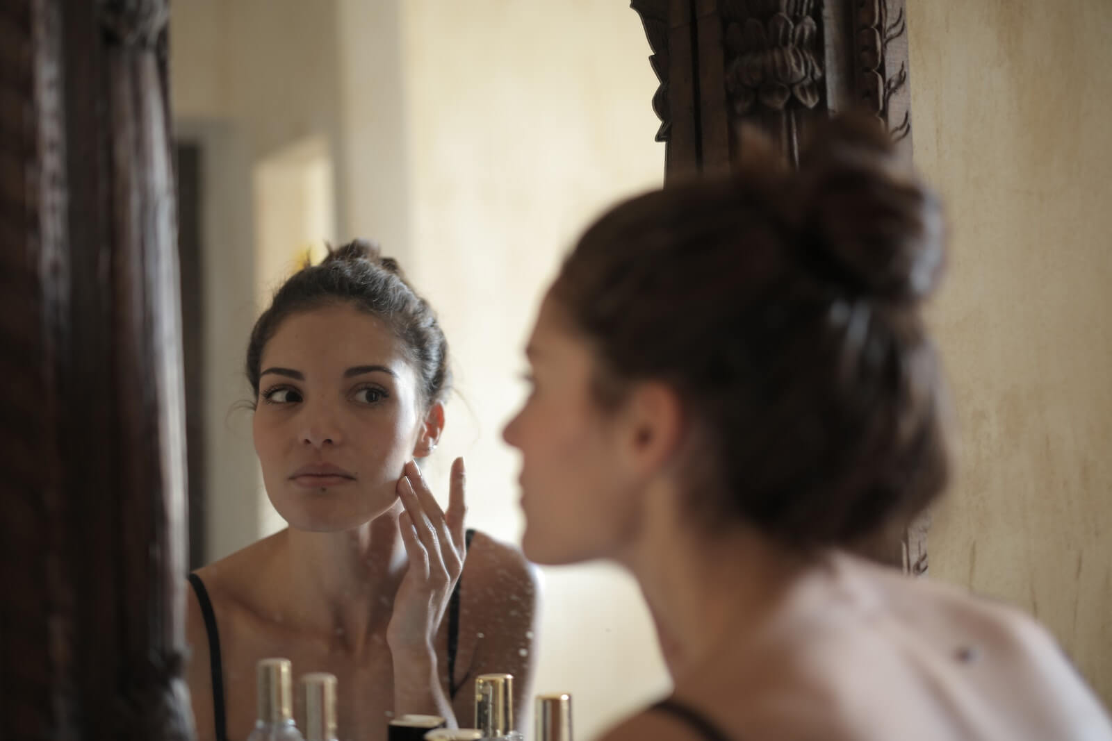 Woman doing skincare in front of mirror