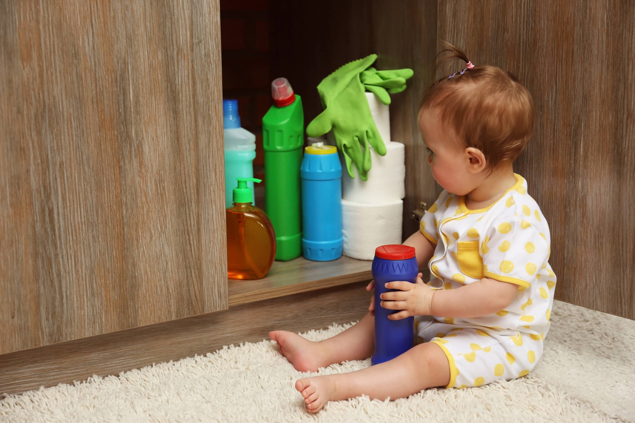 Little girl playing with detergents in kitchen