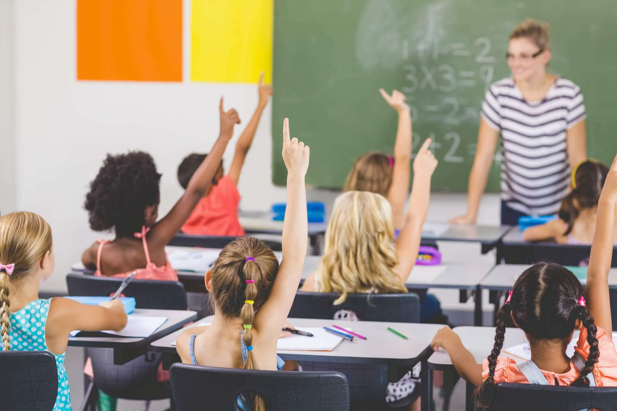 Children raising hands in classroom