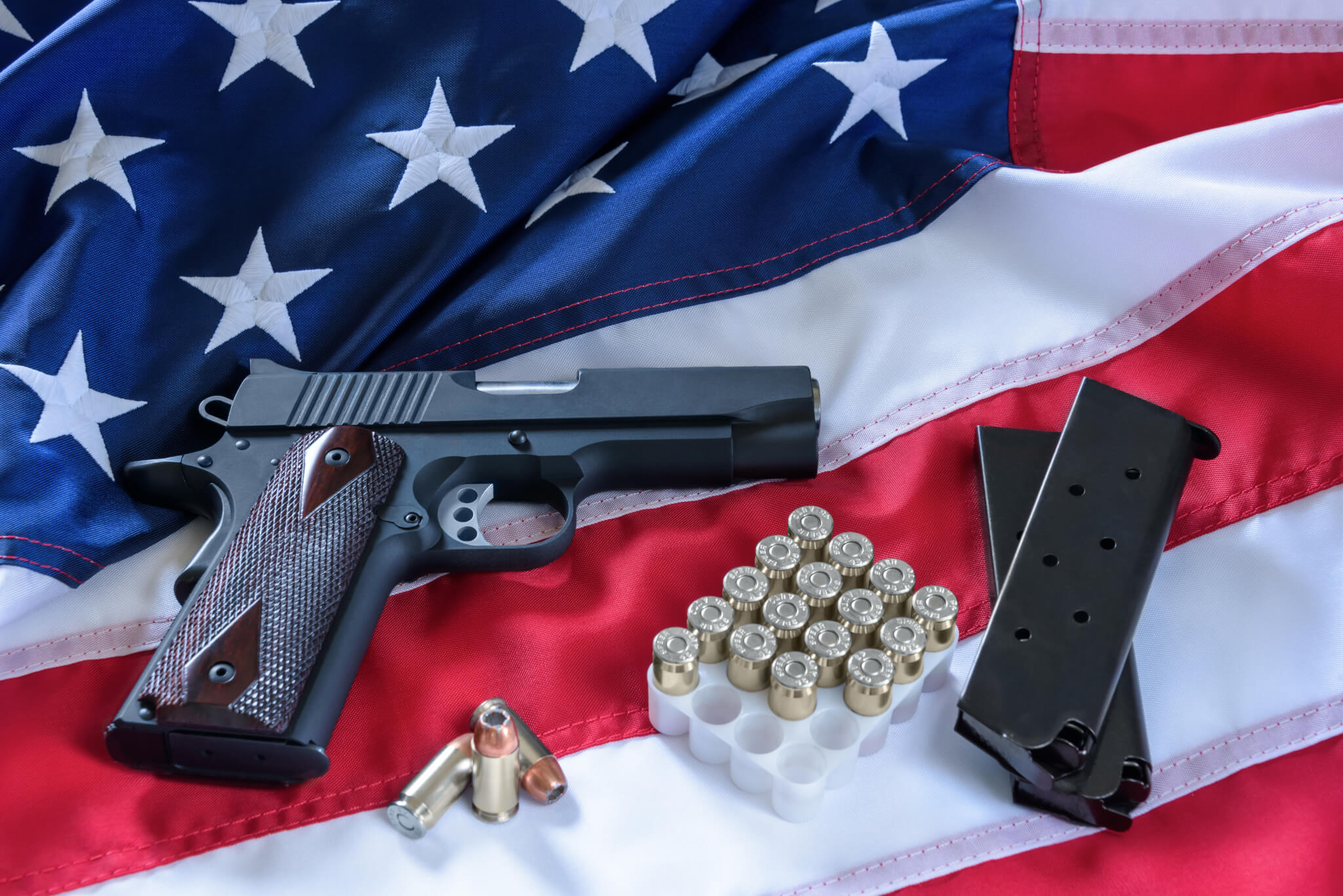 Gun with ammo on an American flag: gun control and gun rights debate