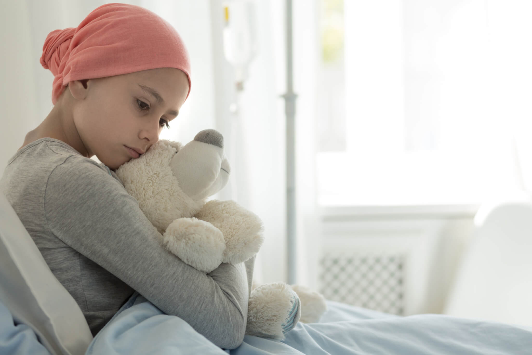 Young girl with cancer hugging teddy bear