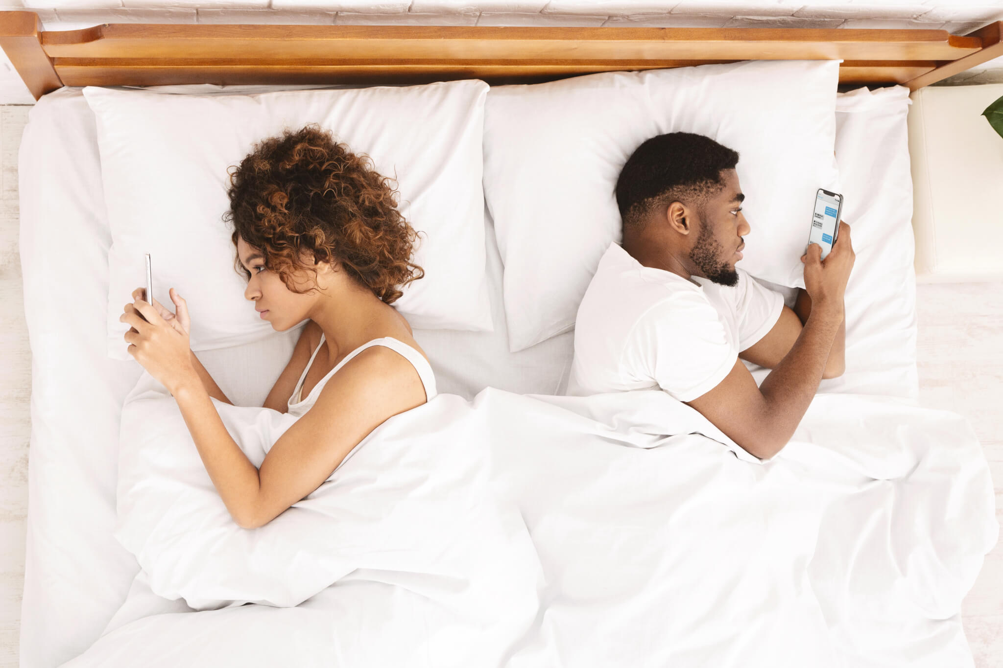 Couple using their smartphones while in bed