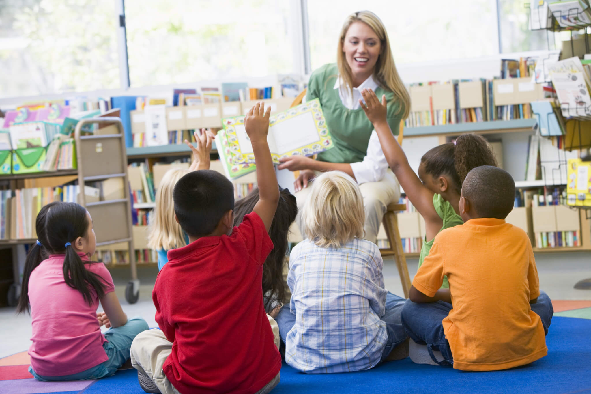 Kindergarten teacher reading to children in library