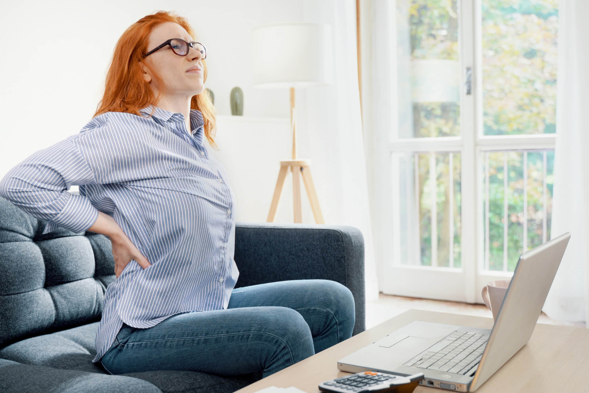 Woman dealing with back pain while working remotely from home