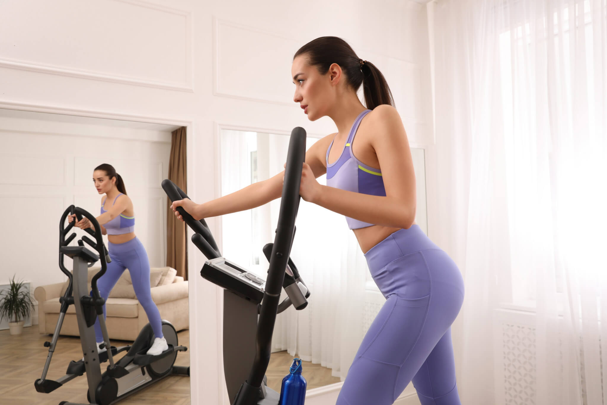 Woman exercising at home using elliptical machine