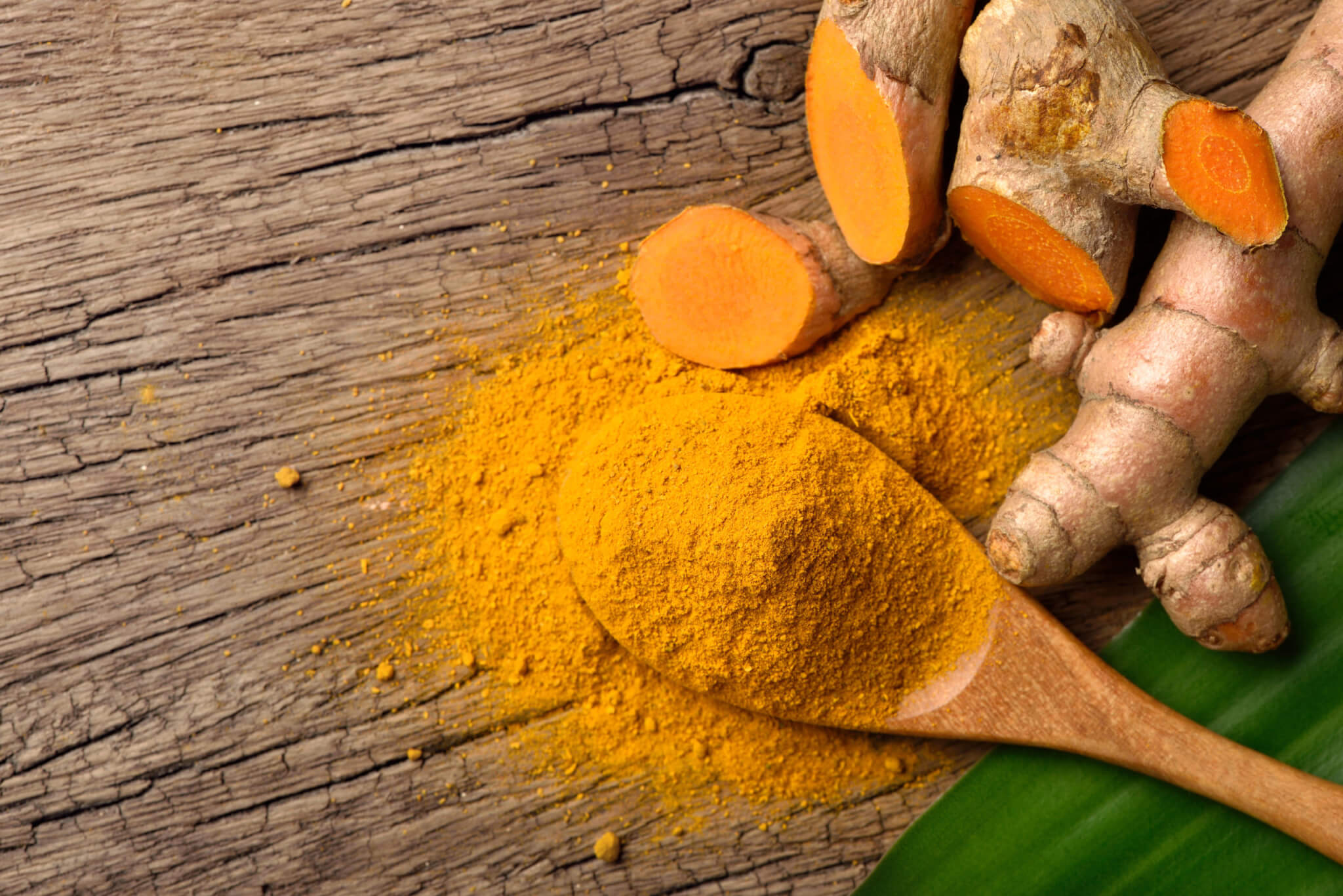 Flat lay (top view) of Turmeric (curcumin) powder in wooden spoon