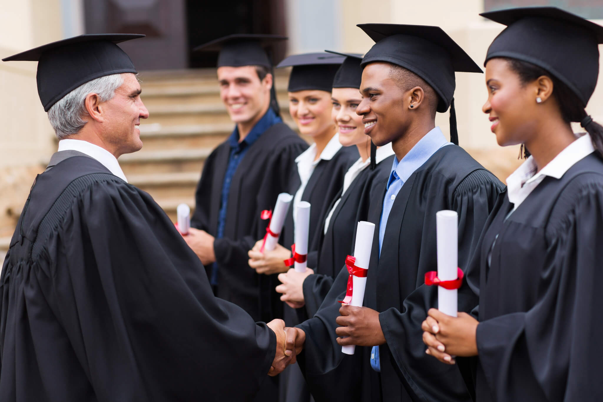 Students at college graduation, dean gives diplomas to graduates