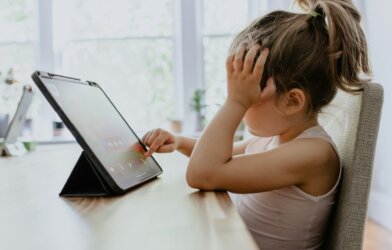 girl in white tank top using black tablet computer