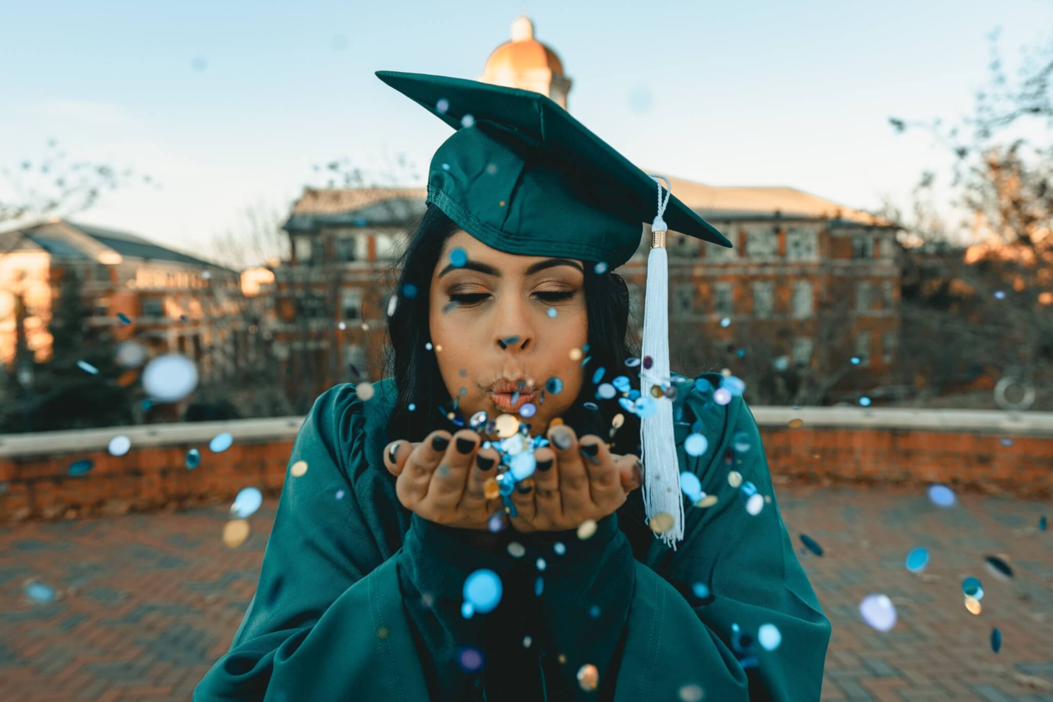 a graduate blowing confetti