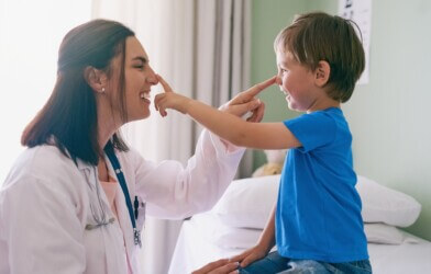 Doctor playing and laughing with boy patient.