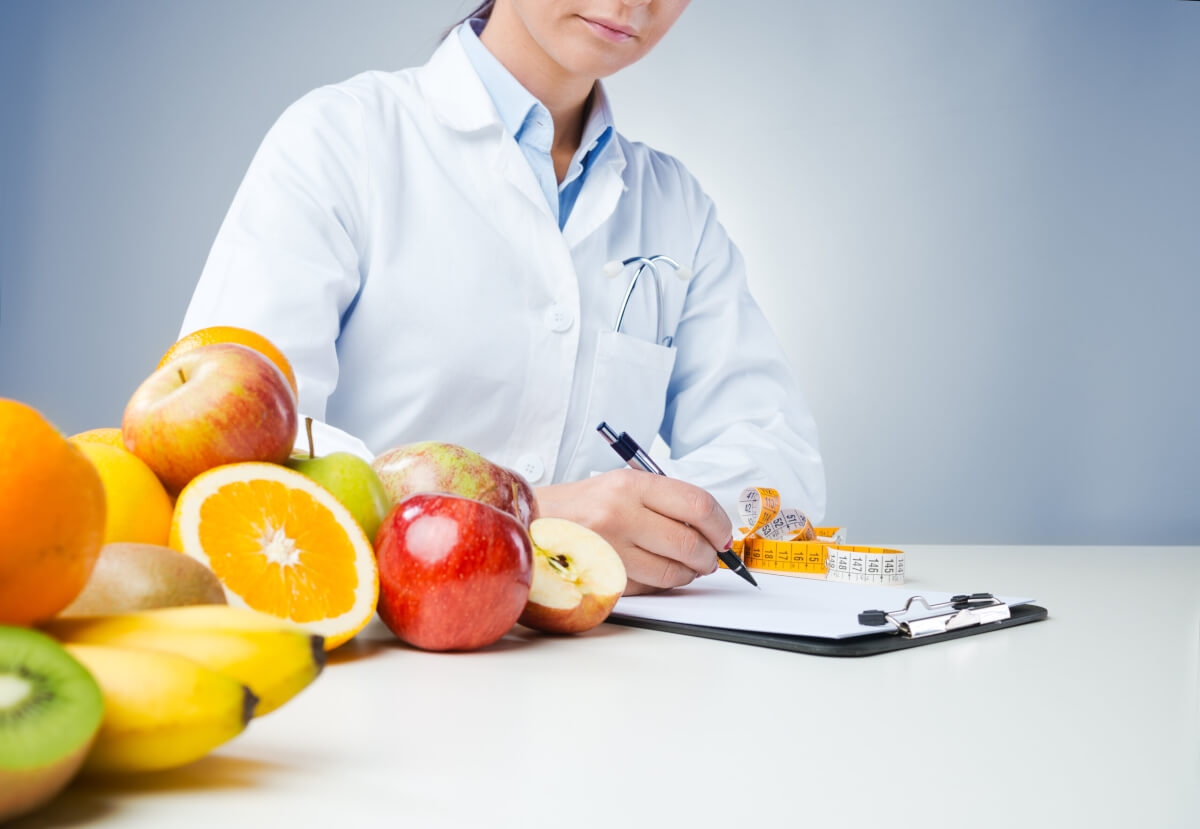 Doctor writing medical records with fresh fruit in foreground