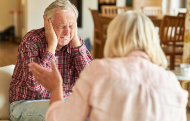 Senior man covers his ears during an argument with another senior