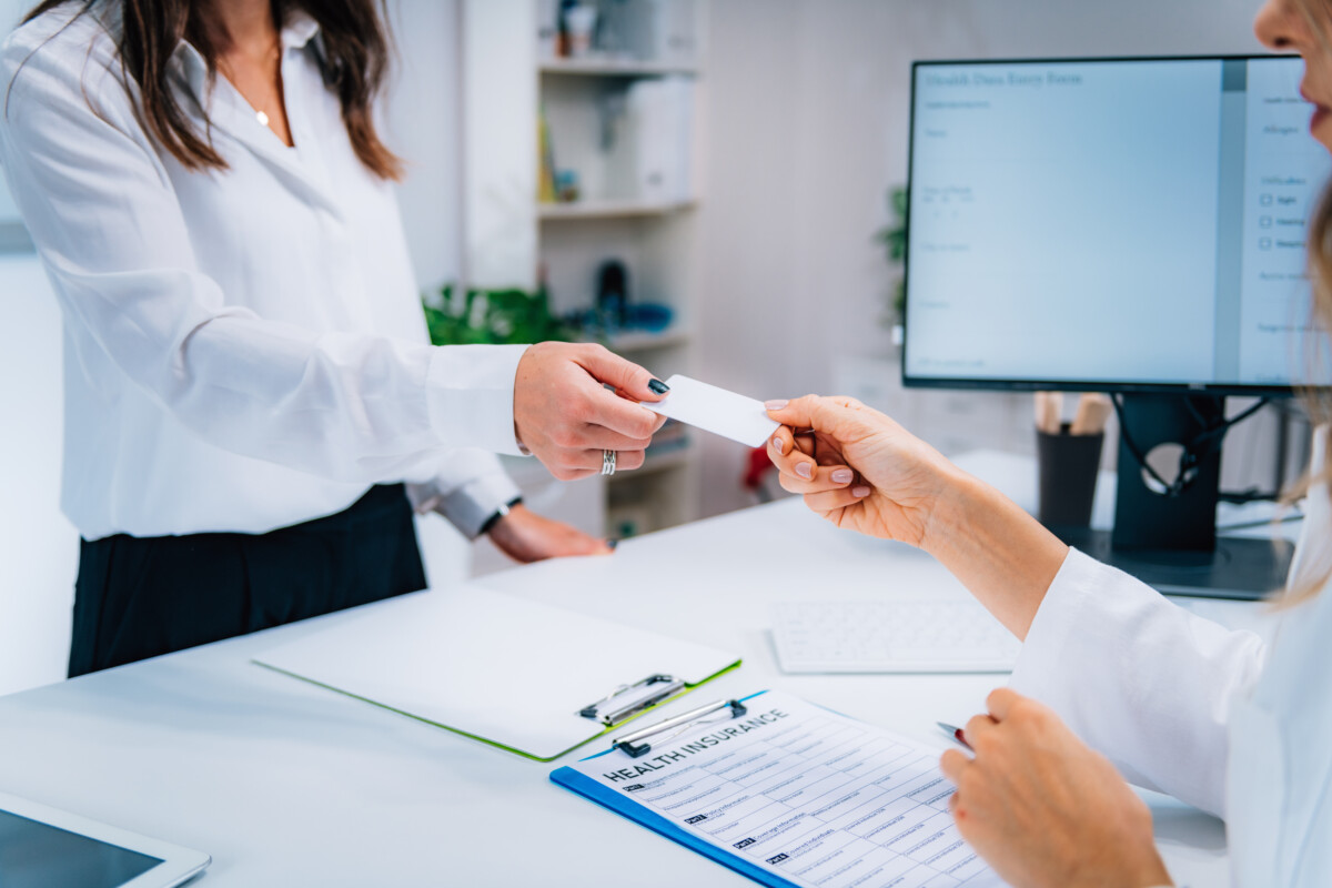 patient giving healthcare worker insurance card