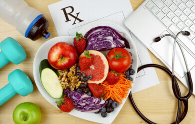 Prescription for good health overhead with stethoscope, healthy fresh food and exercise equipment.