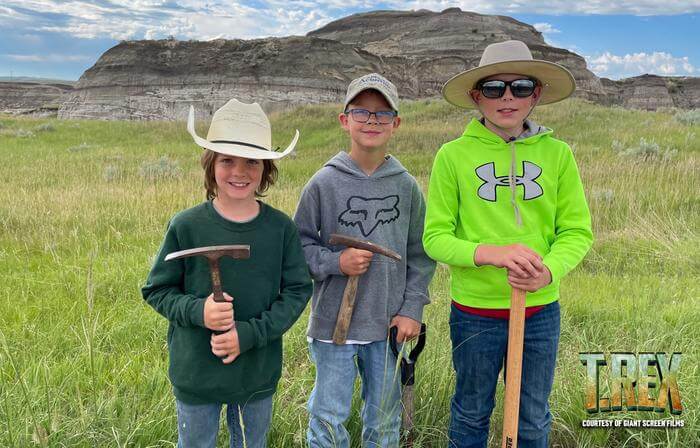 (L-R): Liam Fisher, Kaiden Madsen and Jessin Fisher, then 7, 9 and 10, made the discovery of a lifetime near their North Dakota home in 2022: the remains of a rare teenage Tyrannosaurus rex that could rewrite history. An award-winning Giant Screen Films documentary crew, renowned palaeontologists led by Dr. Tyler Lyson of the Denver Museum of Nature & Science, several of the world’s foremost natural history museums, and top animators have partnered to present the kids’ discovery in dramatic cinematic fashion. Debuting June 21, T.REX will roar in 100 museum theatres worldwide. 