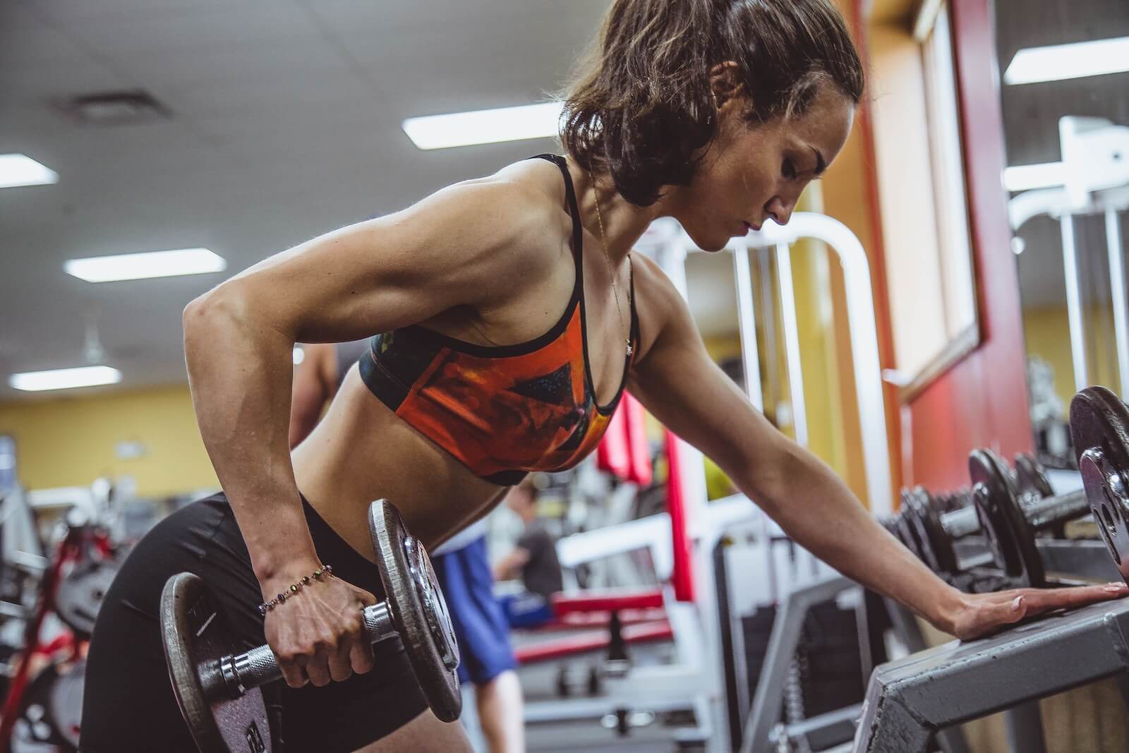 Woman doing bent over rows while lifting weights at the gym