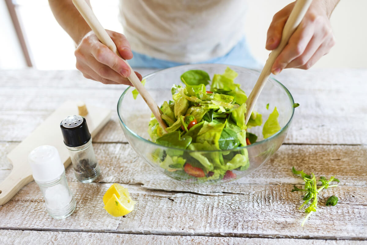 Person making a salad in a bowl