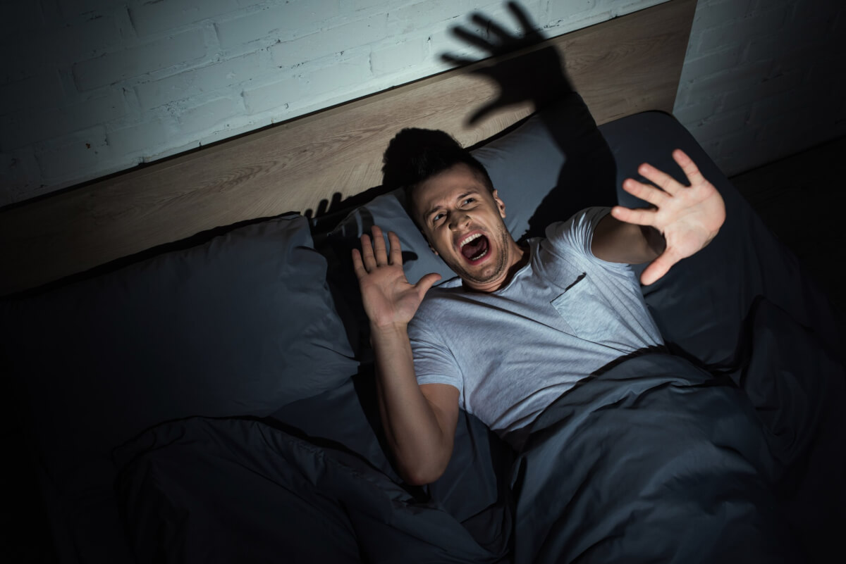 Man screaming from a nightmare in bed