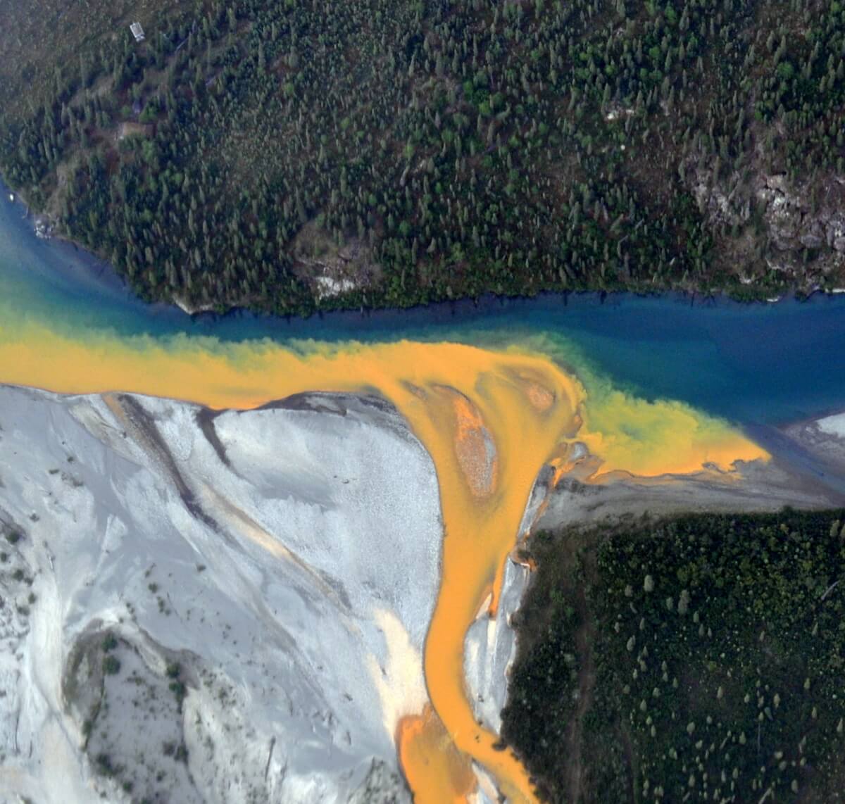 An aerial view of the Kutuk River in Alaska's Gates of the Arctic National Park that looks like orange paint spilling into the clear blue water.