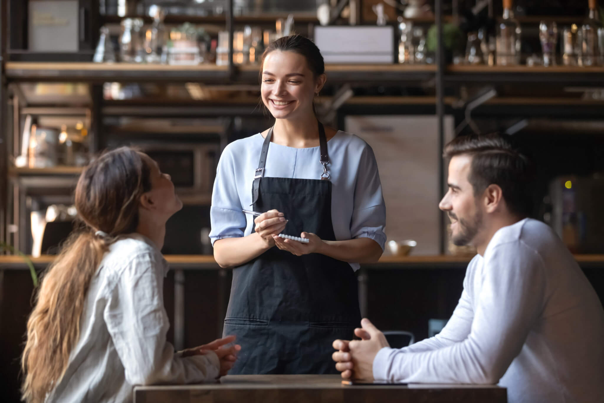 Smiling waitress hold notepad take order serving couple customers