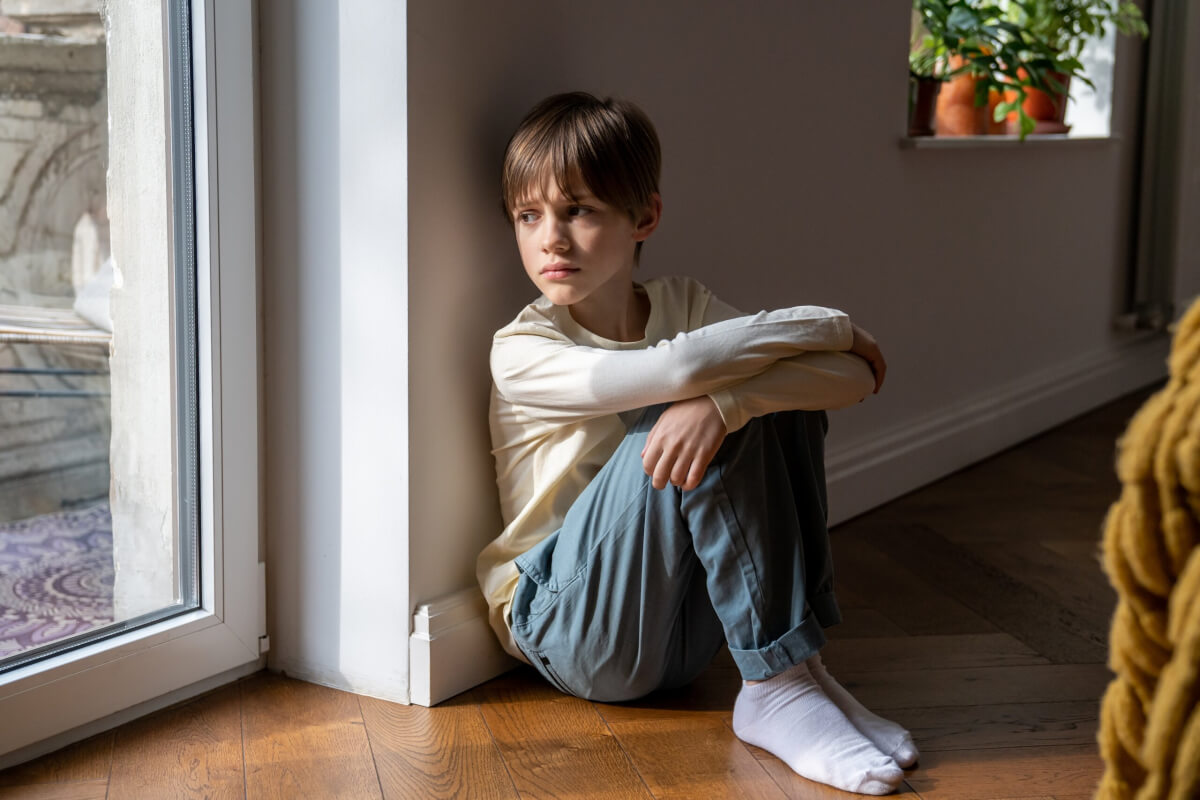 Sad, lonely child looking out the window