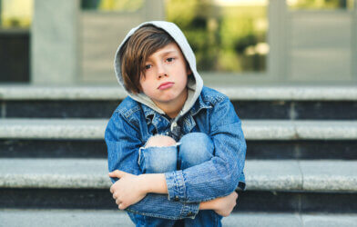 Sad teen child sitting alone on steps