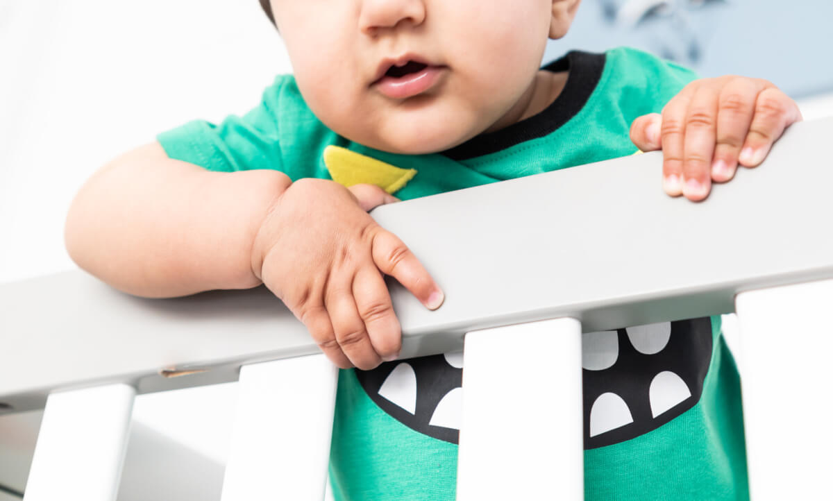 A baby behind a bed rail