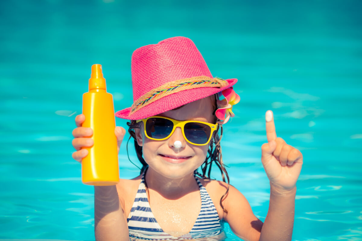 A little girl applying sunscreen in the ocean