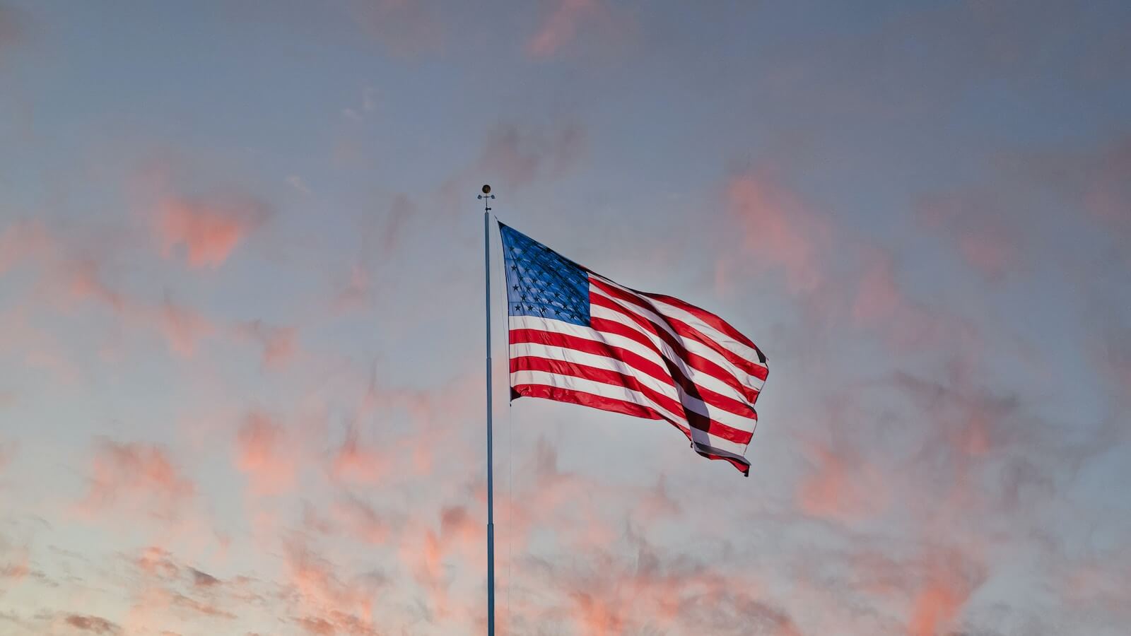 usa flag on pole under sunset sky with clouds