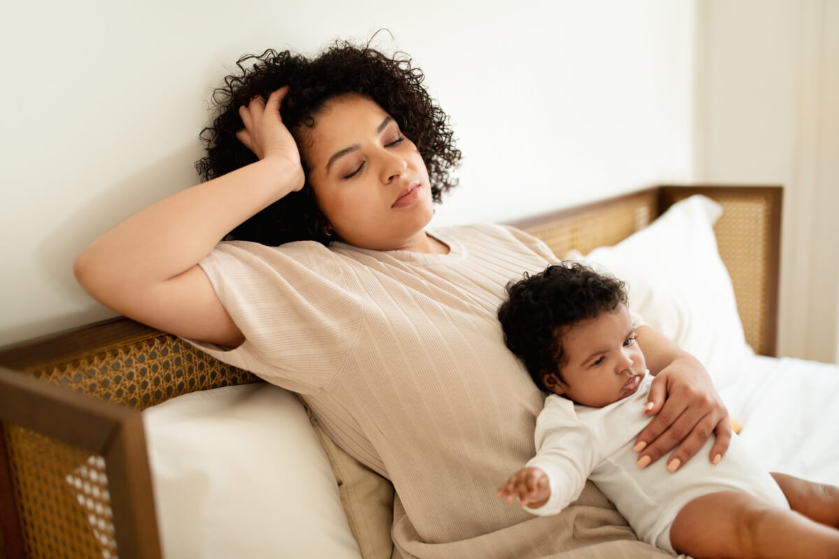 Tired mother lying in bed with her baby